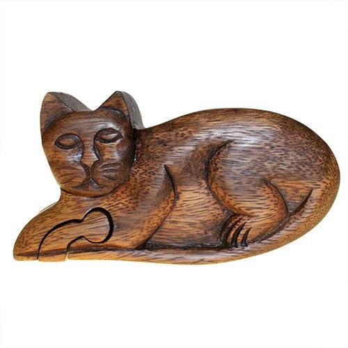 A wooden sculpture of a reclining cat lies gracefully, with intricate carvings highlighting the feline's facial features and curled tail. The figure is polished, showcasing the wood's natural grain.