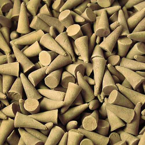 Cones lie scattered, overlapping each other. They are small, uniform, and light brown, suggesting they are incense or craft items. The setting appears dense, with cones covering the entire surface.