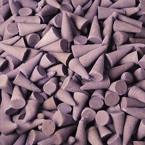 Purple cone-shaped incense pieces lie in a clustered arrangement, densely covering the surface, creating a textured and uniform pattern.