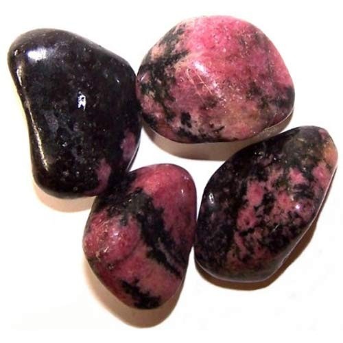 Four tumbled stones, predominantly pink with black markings, rest on a plain white surface. The stones vary in size and shape, appearing polished and smooth.