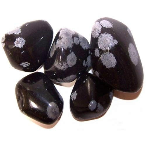 Several polished, black obsidian stones, speckled with white patterns, cluster together on a white surface.