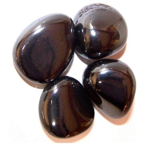 Four smooth, dark, polished hematite stones are arranged together on a plain white surface. The stones reflect light, giving them a shiny appearance.