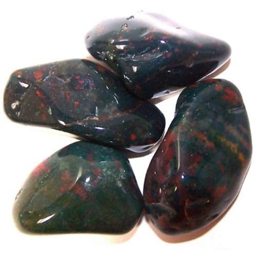 Polished, rounded bloodstones cluster together on a white surface. The stones are primarily dark green with red markings.