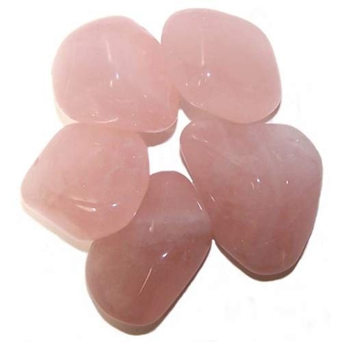 Five polished rose quartz stones sit on a white surface, clustered together with their smooth, rounded forms and pale pink color.