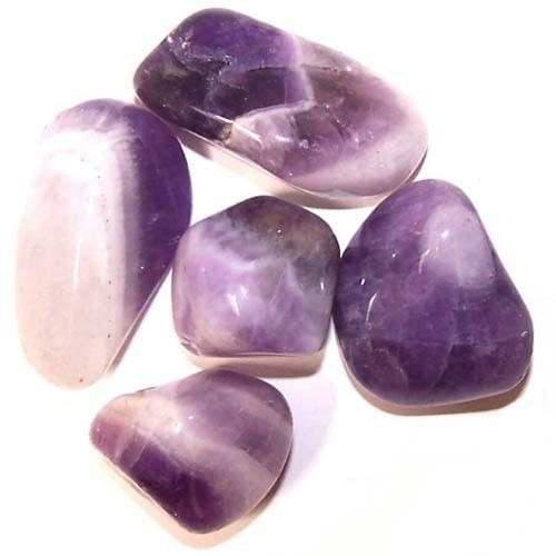 Amethyst stones scatter on a plain white surface, displaying varying shades of purple and white stripes within their smooth, polished surfaces.