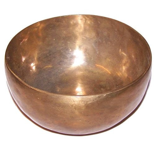 A polished, metallic singing bowl sits stationary, reflecting light on its surface, placed on a white background with no additional objects visible.