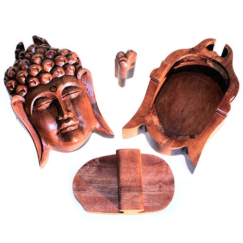 A carved wooden puzzle box features a Buddha head as the main piece. It is disassembled into four parts, including a central peg, against a plain white background.