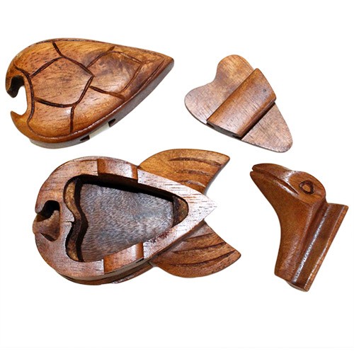 Wooden puzzle pieces resembling parts of an animal are disassembled. The main part looks like a turtle shell, with other pieces making up the head and limbs, lying on a flat surface.