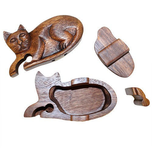 A wooden puzzle box shaped like a sleeping cat, disassembled into separate pieces, including the body, lid, and two small, curved sections, displayed on a white background.