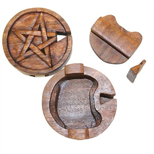 A round wooden puzzle box with a carved pentagram on the lid is separated into pieces, revealing a hollow interior. The pieces are scattered around, showcasing their geometric designs.