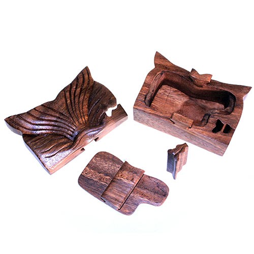 A carved wooden box with a whale tail design is disassembled into several pieces, including a lid and inner compartments, placed on a white surface.