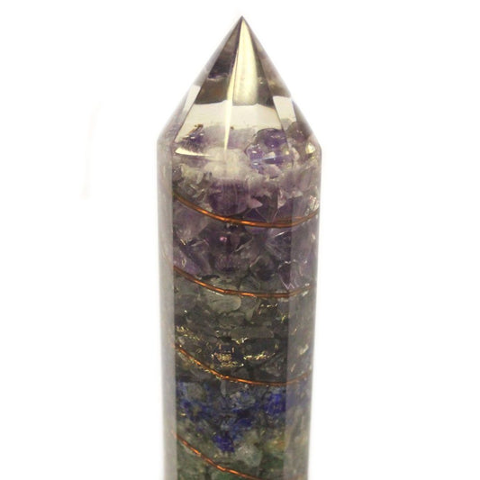 A pointed, clear crystal obelisk showcases multiple bands of purple, gray, and blue minerals inside, separated by thin copper wire, set against a white background.