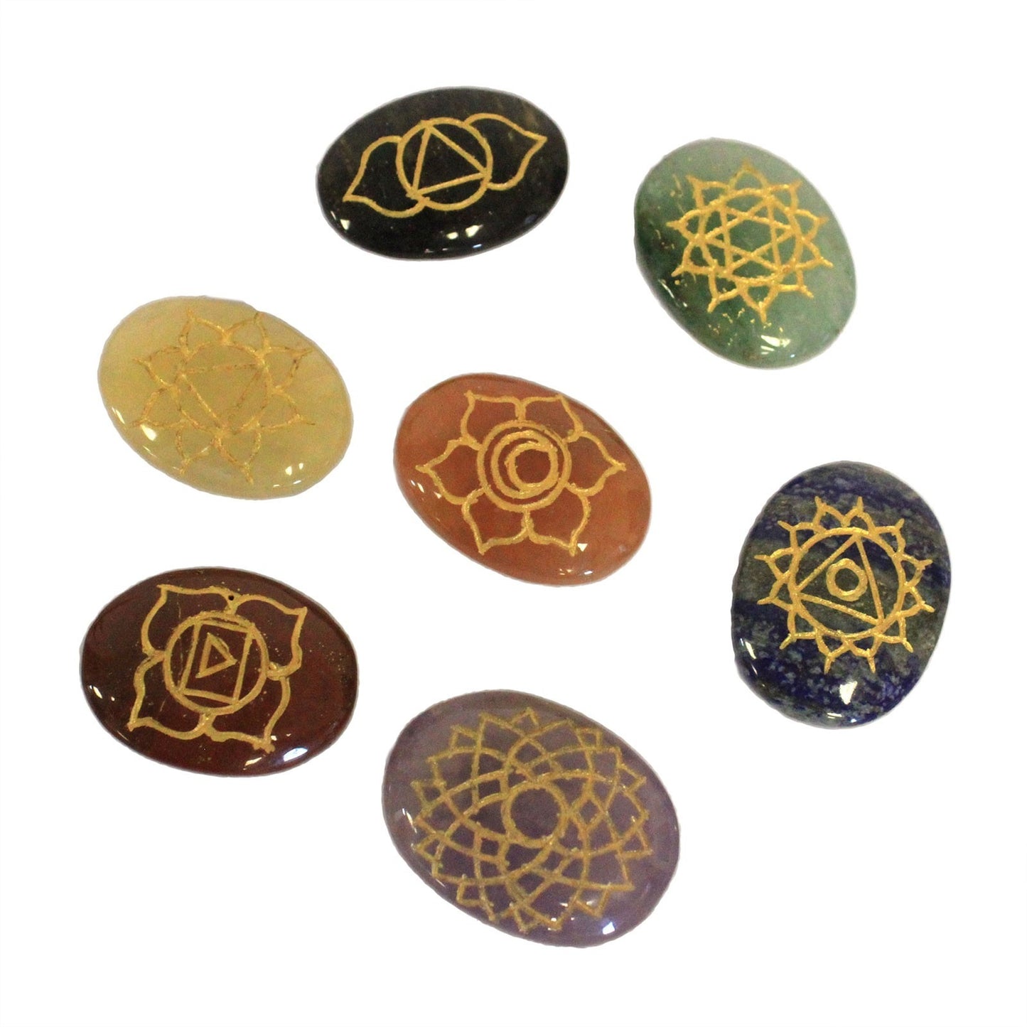 Seven chakra stones, each a different color and marked with a gold symbol, are arranged on a white surface.