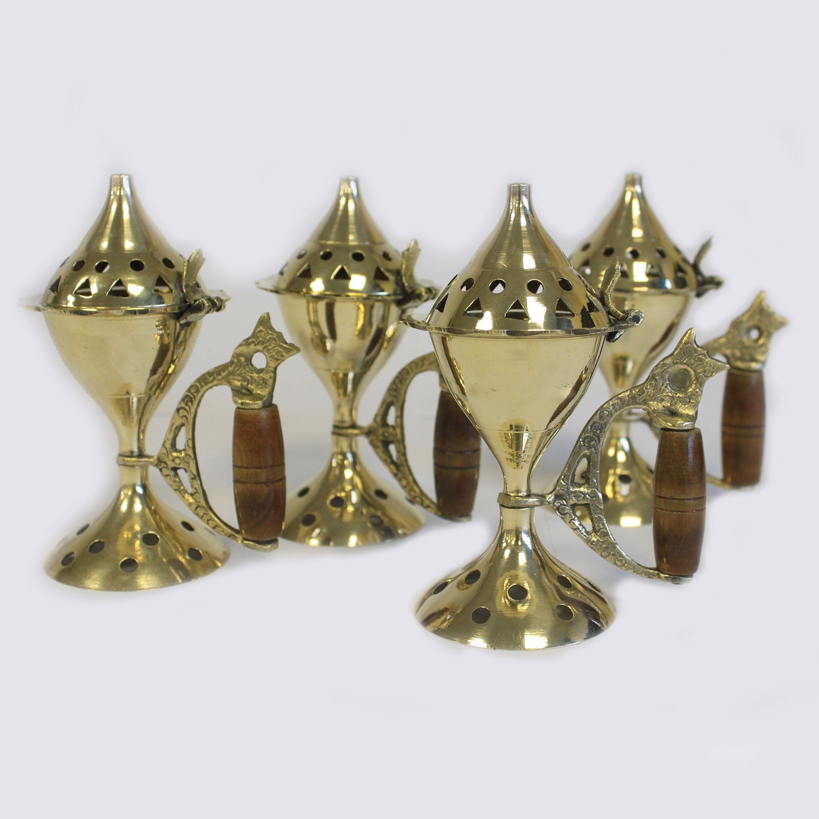 Gold-colored ornamental metal tea holders with wooden handles, featuring tall perforated lids, arranged closely together on a plain light background.