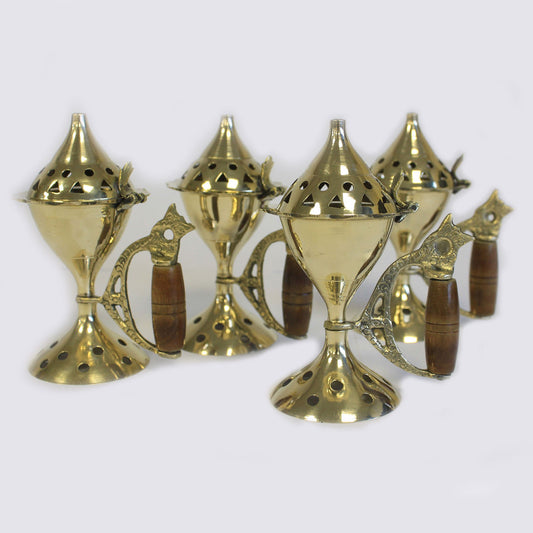 Gold-colored ornamental metal tea holders with wooden handles, featuring tall perforated lids, arranged closely together on a plain light background.