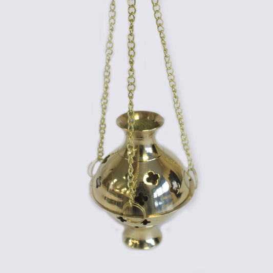 Gold-colored incense burner hangs from three chains, adorned with clover-shaped cutouts, against a plain gray background.