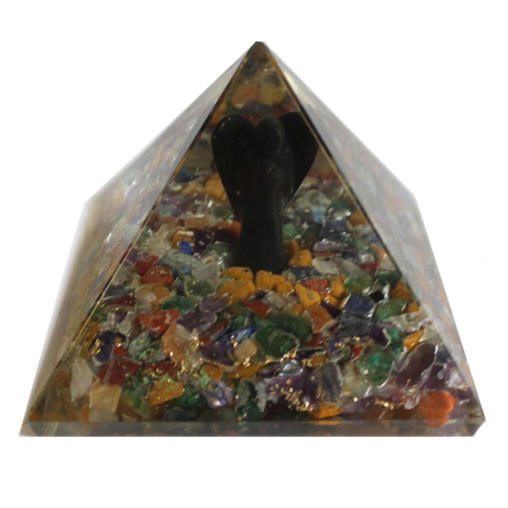 A pyramid-shaped paperweight holds a black figurine, surrounded by colorful gemstone pieces and flecks of gold, within its transparent resin form.