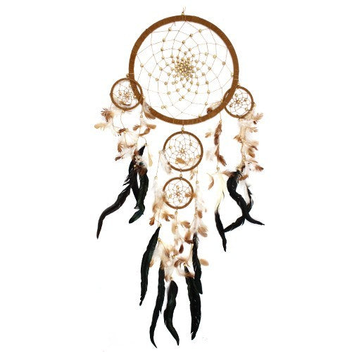 A large dreamcatcher hangs against a white background. It features a brown hoop, beaded web, and multiple smaller rings adorned with tan and black feathers.