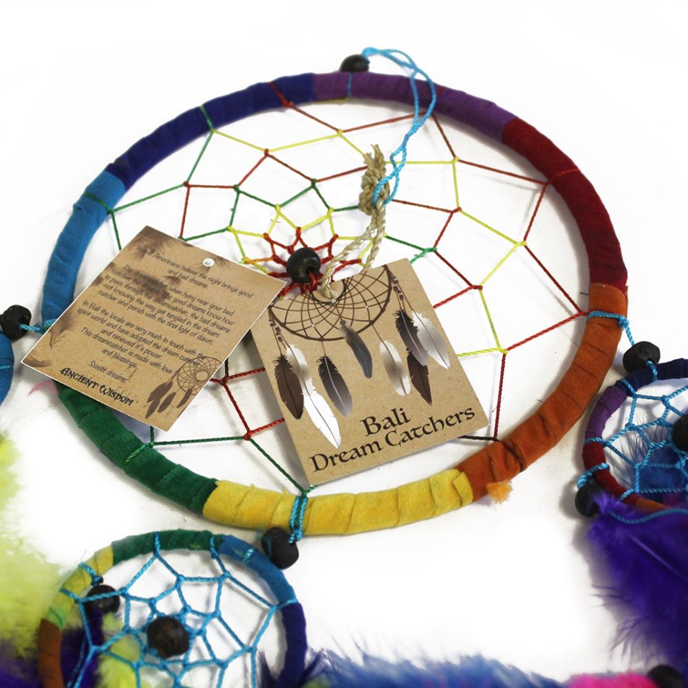 A multicolored circular dreamcatcher hangs, adorned with feathers. It features a woven net and is accompanied by a descriptive tag reading: "ANCIENT WISDOM Bali Dream Catchers".