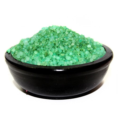 Green granular material rests in a dark bowl.