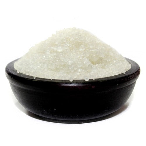 A pile of small, off-white granules rests in a dark bowl.