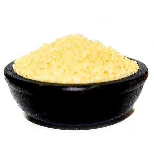 Pale yellow couscous rests in a dark bowl on a white background.