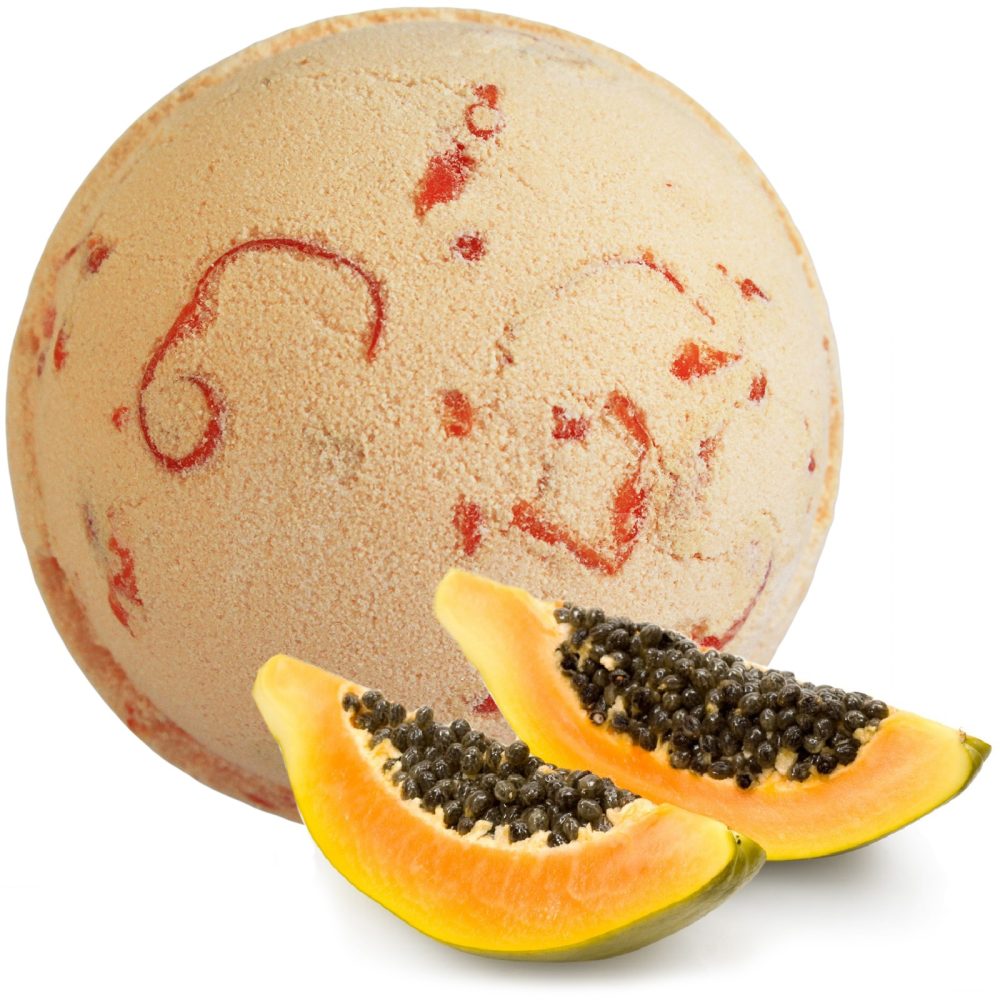 A round bath bomb with red swirls sits beside two slices of papaya, showcasing its seeds and vibrant orange flesh against a white background.