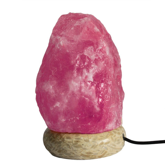 A pink salt lamp sits on a beige, textured base with a black cord extending from it, set against a plain white background.