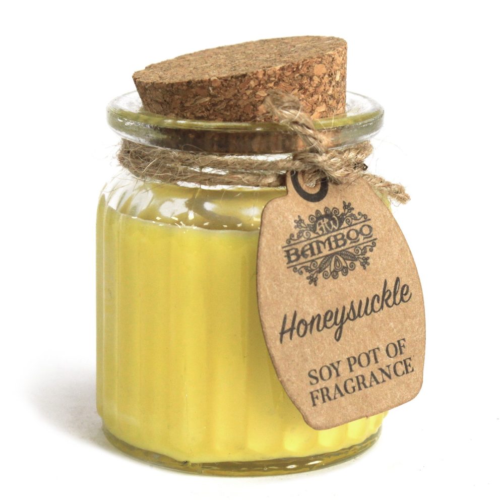 A yellow candle sits in a glass jar sealed with a cork lid and twine. A brown tag reads "BAMBOO Honeysuckle SOY POT OF FRAGRANCE". The object is on a white surface.