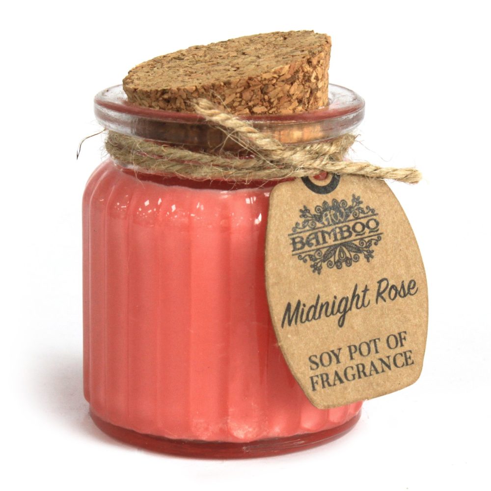 A ribbed glass jar filled with rose-colored wax has a cork lid tied with twine. A tag reads "BAMBOO Midnight Rose SOY POT OF FRAGRANCE".