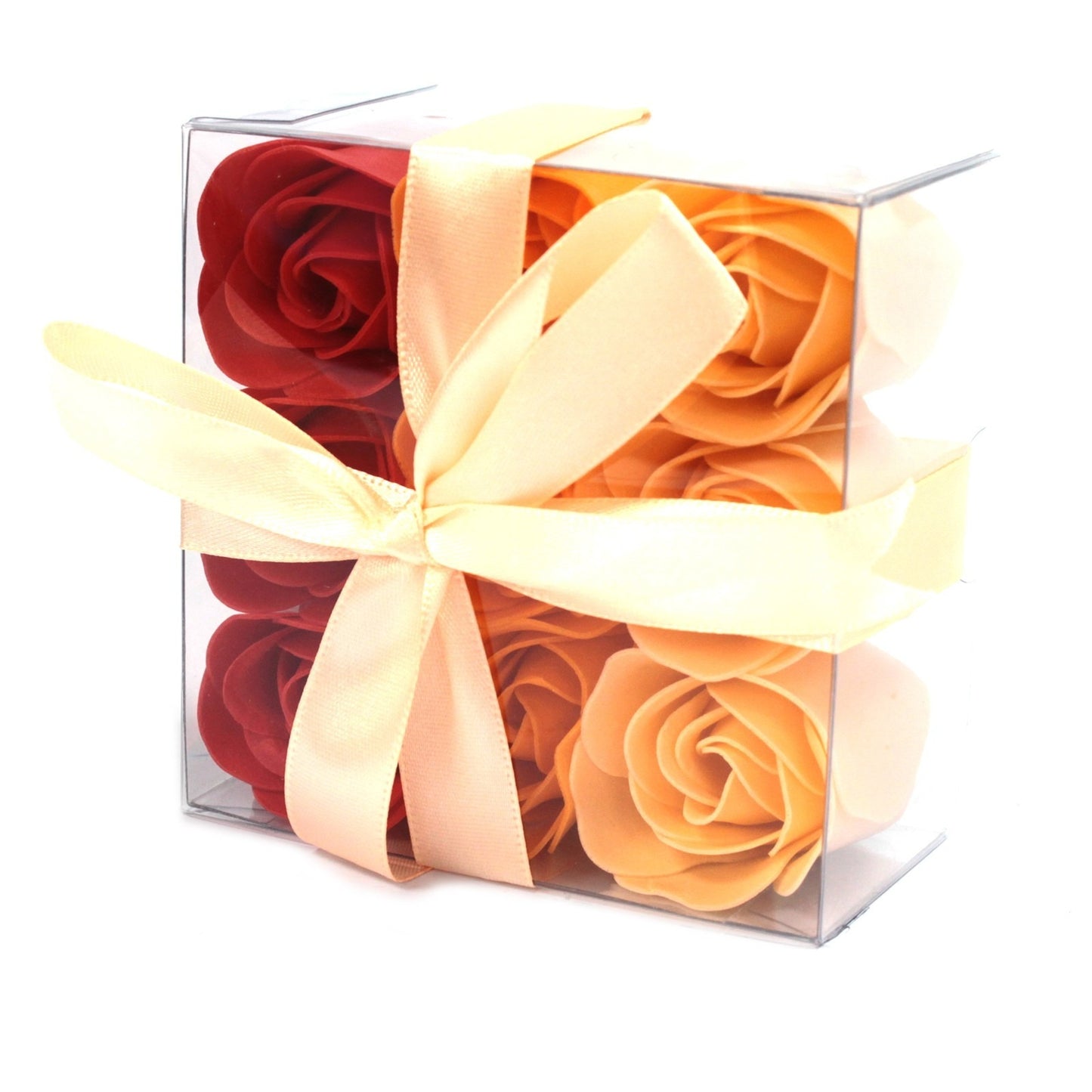 Floral soaps arranged in a clear box, are tied with a creamy-peach ribbon, set against a plain, white background.