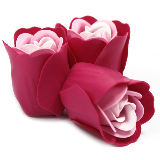 Three pink artificial roses cluster together, two upright and one reclining, showing layered petals in deep magenta and pale pink against a white background.