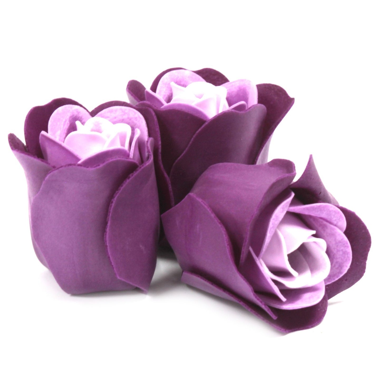 Three purple rose-shaped soaps sit nestled together, the inner petals a lighter lavender hue, on a stark white surface.