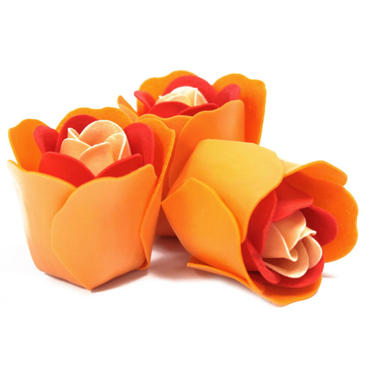 Three foam roses sit clustered, their orange outer petals unfolding around layered red and pale cream inner petals, photographed on a bright white background.