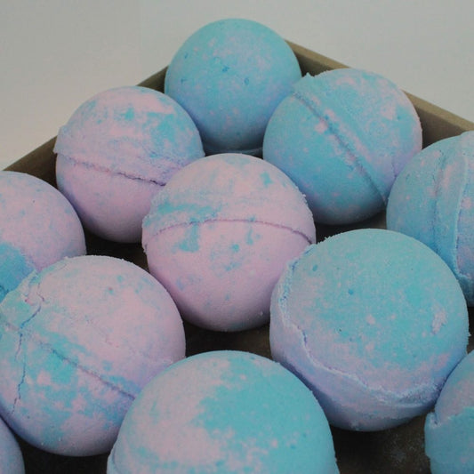 Colorful bath bombs sit in a container, displaying a pastel blue and pink marbled pattern, creating a vibrant and soothing aesthetic in a bathroom setting.