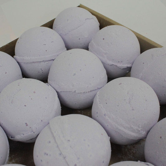 Purple bath bombs are arranged neatly in a cardboard holder, resting on a flat surface.
