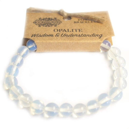An opaline bead bracelet is displayed on a white surface, partially tucked beneath a tan card that reads: “ACCESSORIES POWER BRACELET OPALITE Wisdom & Understanding”.