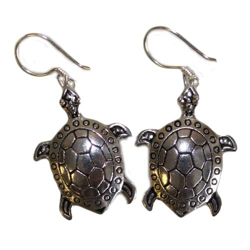 Two turtle earrings hang, facing different directions. They are silver and dangle from shepherd's hooks, isolated on a white background.