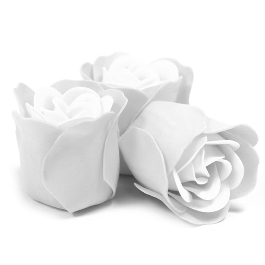 Three white rose-shaped foam decorations lie clustered on a white background in a close-up studio shot.
