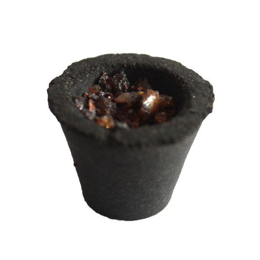 A small, black, cup-shaped container filled with dark, rough granules. The object appears isolated against a white background, highlighting its textured surface and contents.