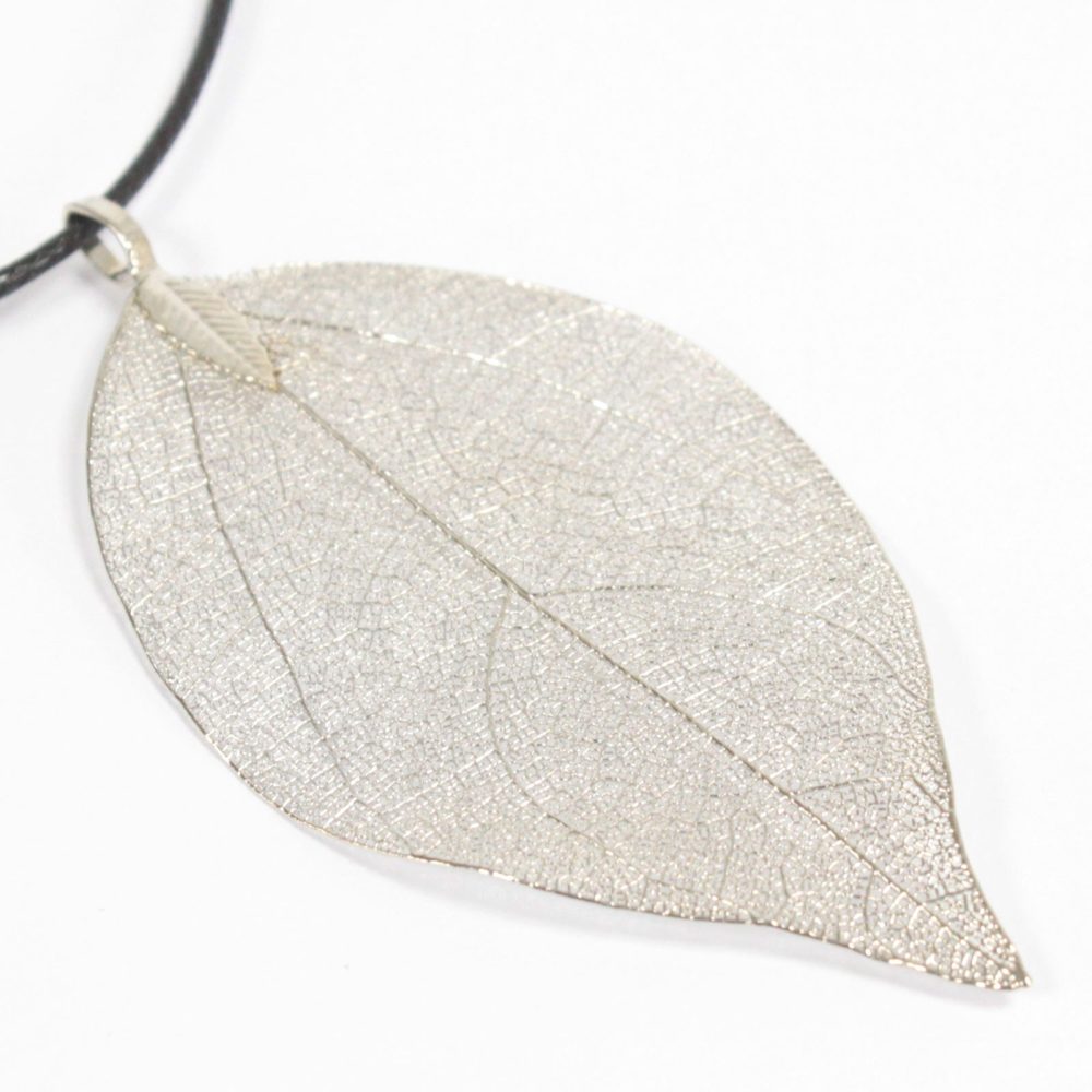A silver leaf pendant hangs from a black cord necklace, presented against a bright white backdrop. The leaf displays a detailed, skeletal vein structure.