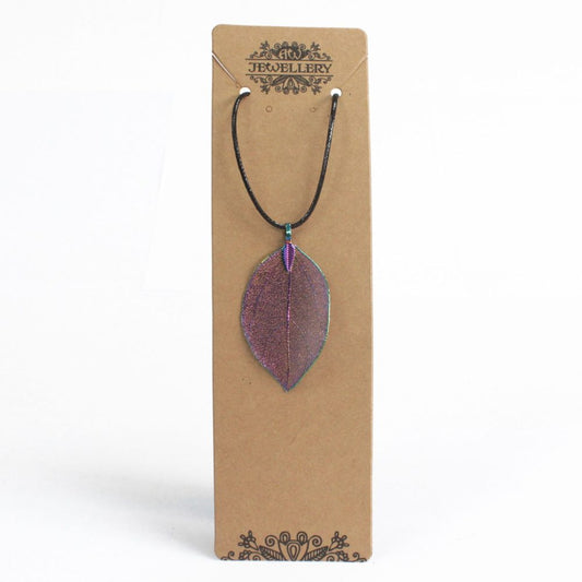 A leaf pendant necklace hangs from a brown cardboard tag. The text on the tag reads "JEWELLERY" in stylized lettering. The background is a plain white surface.
