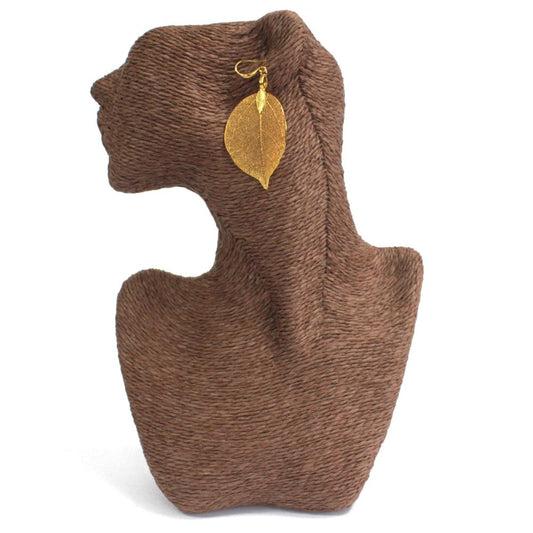 A golden leaf earring hangs from a brown mannequin head and neck. The mannequin is against a white background.