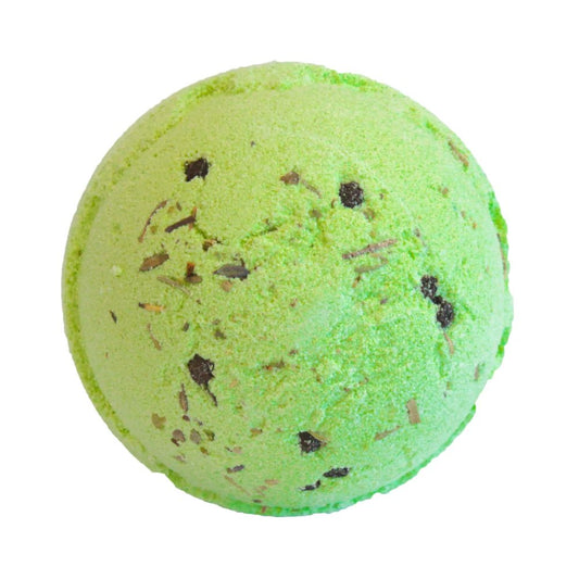 A green spherical bath bomb with small, dark specks is shown on a plain white background, suggesting readiness for use in a bath.