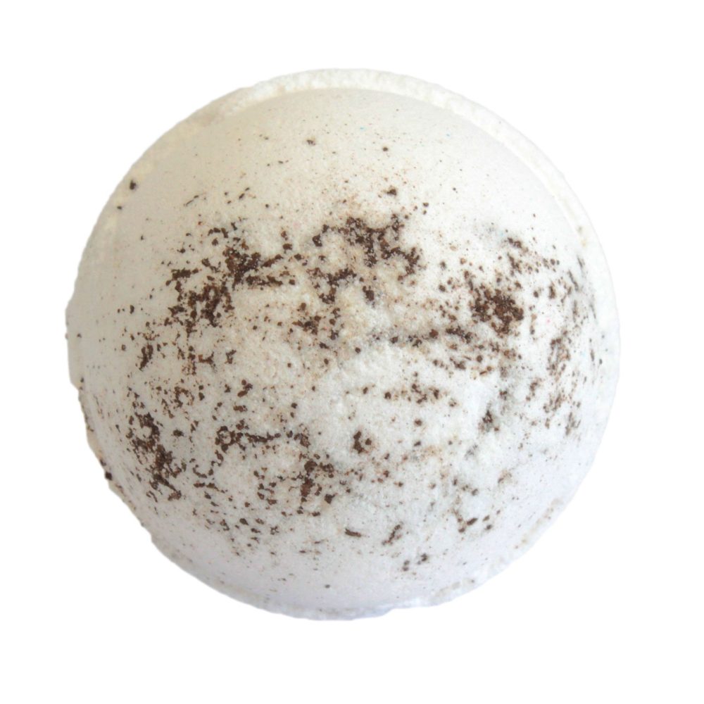 A white bath bomb with scattered brown speckles sits against a plain, white background, ready for use in a bathing setting.