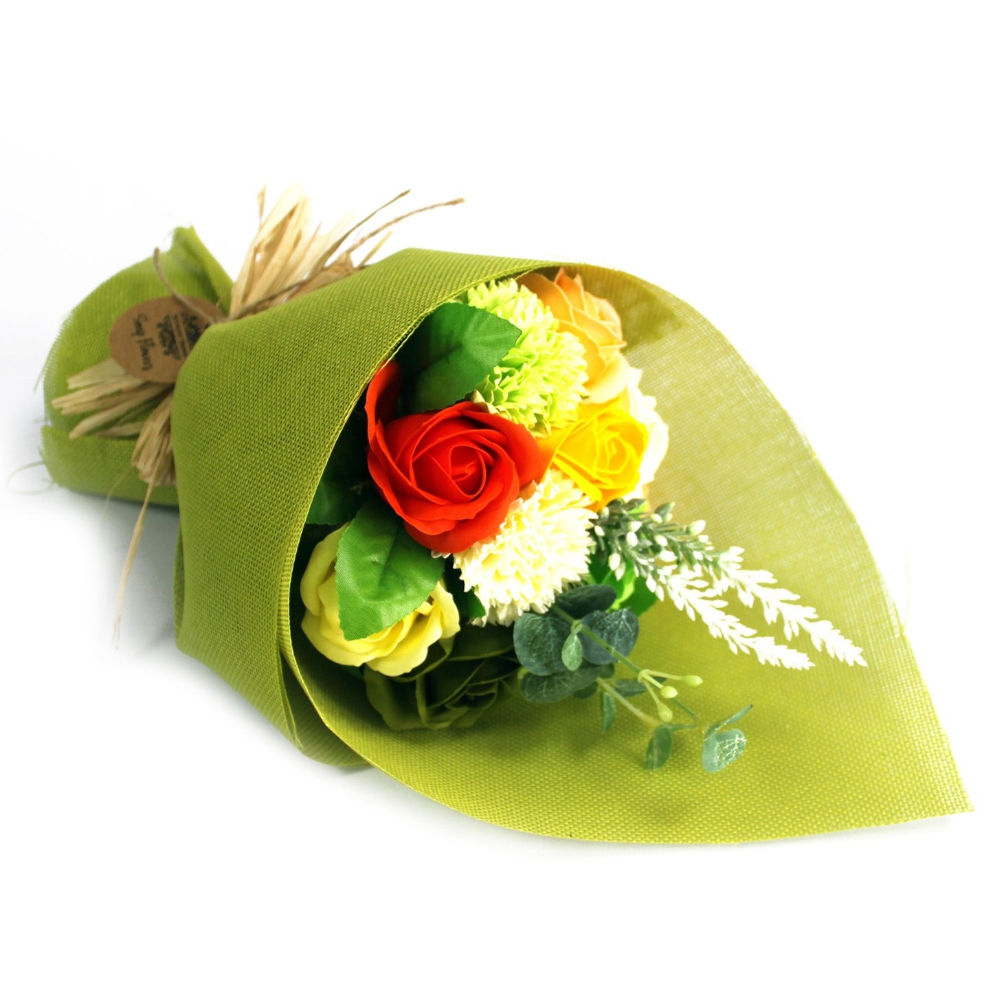 Bouquet of colorful roses, carnations and greenery rests wrapped in a textured green paper on a white background. "Soap Flowers" is legible on a tag.