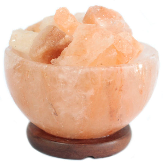 Orange and white crystal chunks are resting in a round, polished salt bowl on a wooden base, isolated against a white background.