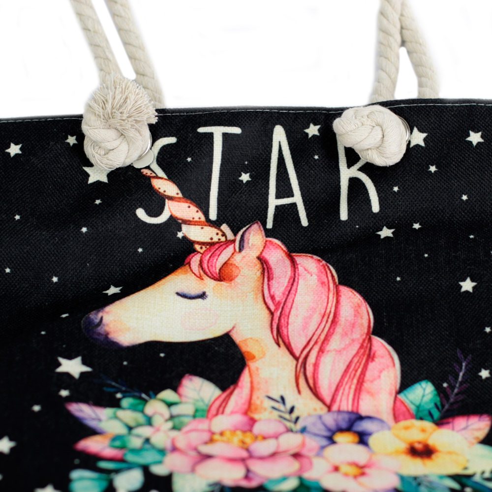 A black tote bag displays an illustration of a unicorn with a floral arrangement; white stars are scattered on the bag’s surface along with the word "STAR" in white lettering at the top. The bag has rope handles.