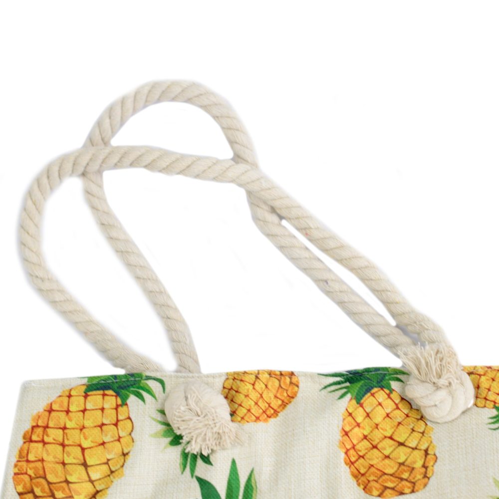 A tote bag featuring a pineapple pattern is equipped with thick, light-colored rope handles against a bright, white background.