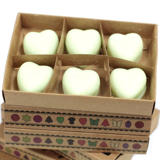 Heart-shaped wax melts are arranged in a cardboard box. The box is decorated with a repeating pattern of small icons. Another similar box is stacked below.